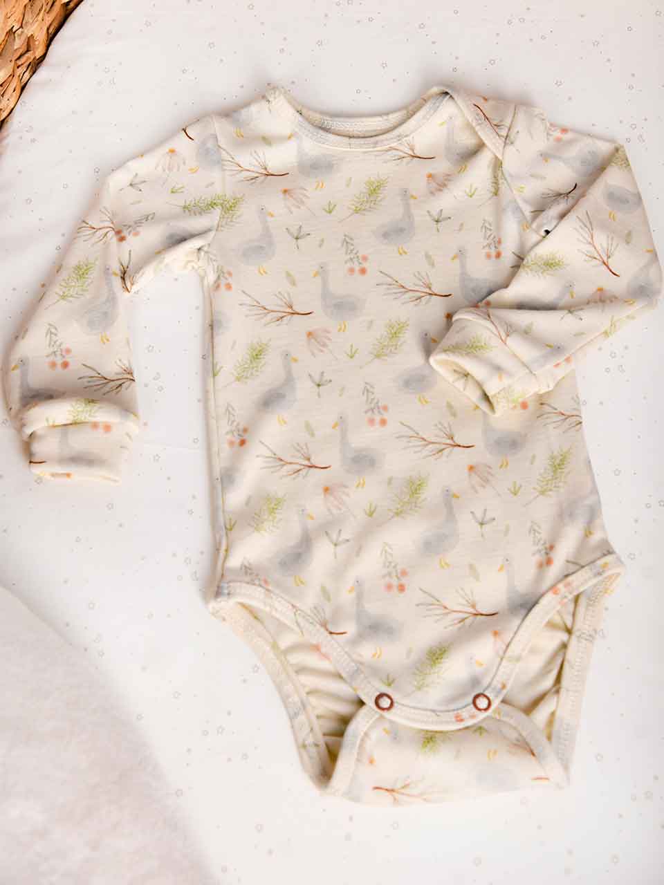 Baby Body aus hochwertiger Wolle und Seide mit süßem Gänse-Motiv auf beigen Hintergrund. Der Body hat einen halbamerikanischen Ausschnitt. Für Babys von 0-2 Jahren geeignet.