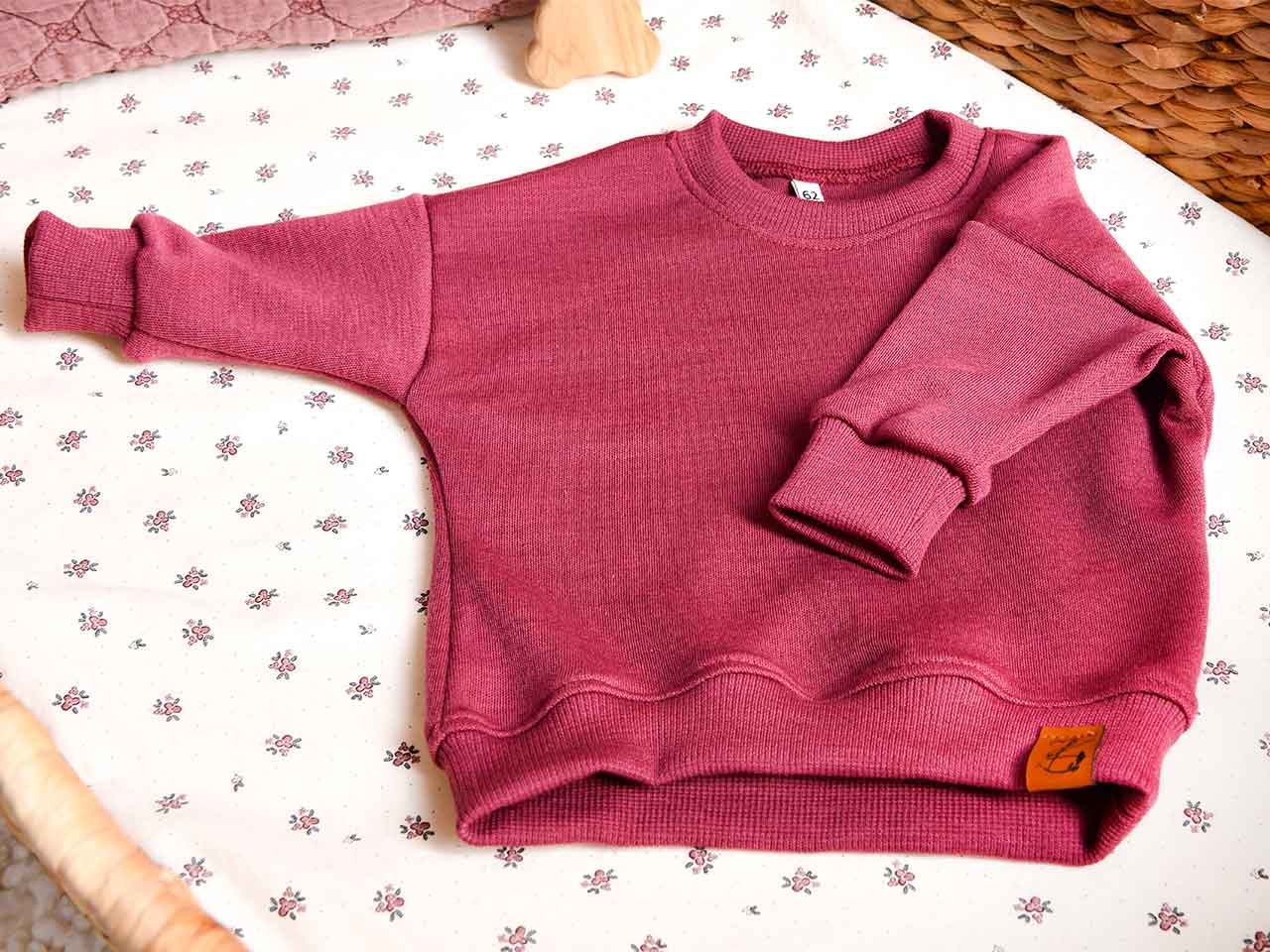 Oversize Sweater für Babys aus natürlicher Wolle in der Farbe Beere. Für Babys im Alter von 0-2 Jahren.