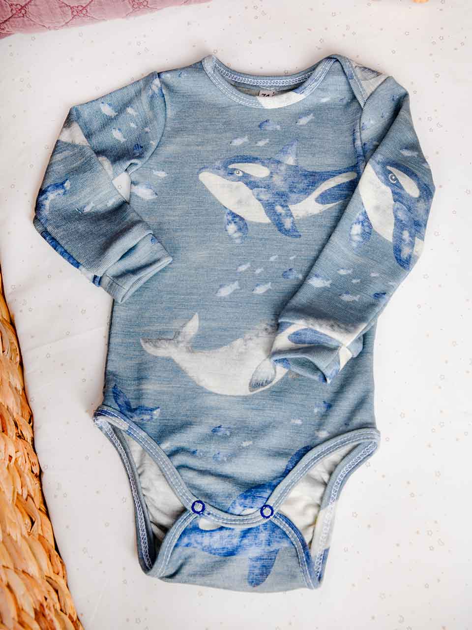 Body aus feiner Merinowolle und Lyocell mit süßem Wal-Motiv mit blauem Hintergrund. Geeignet für Babys von 0-2 Jahren.